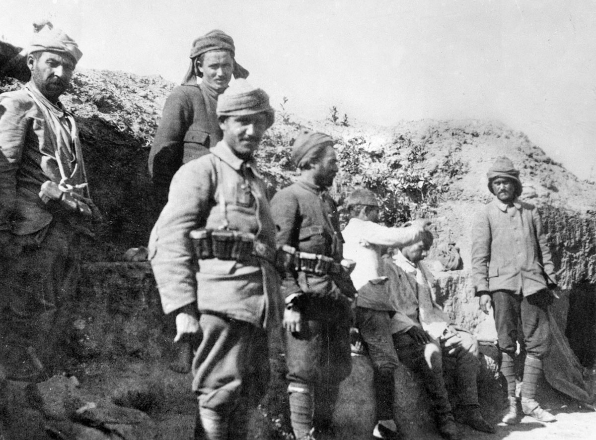 A group of Turkish soldiers in a deep trench with one soldier cutting another's hair. This is probably a reserve trench as some of the soldiers are not armed.